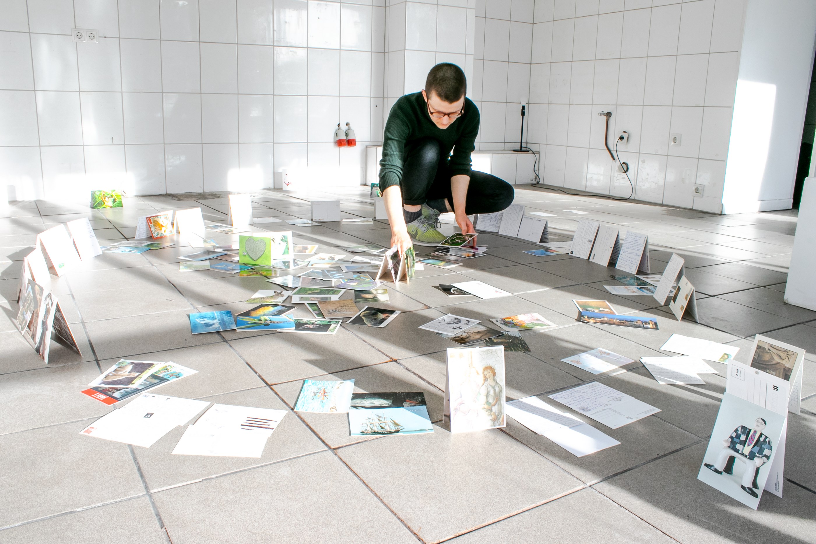 Eddie de Goër arranging postcards, in the middle of a partly collapsed ring of postcards