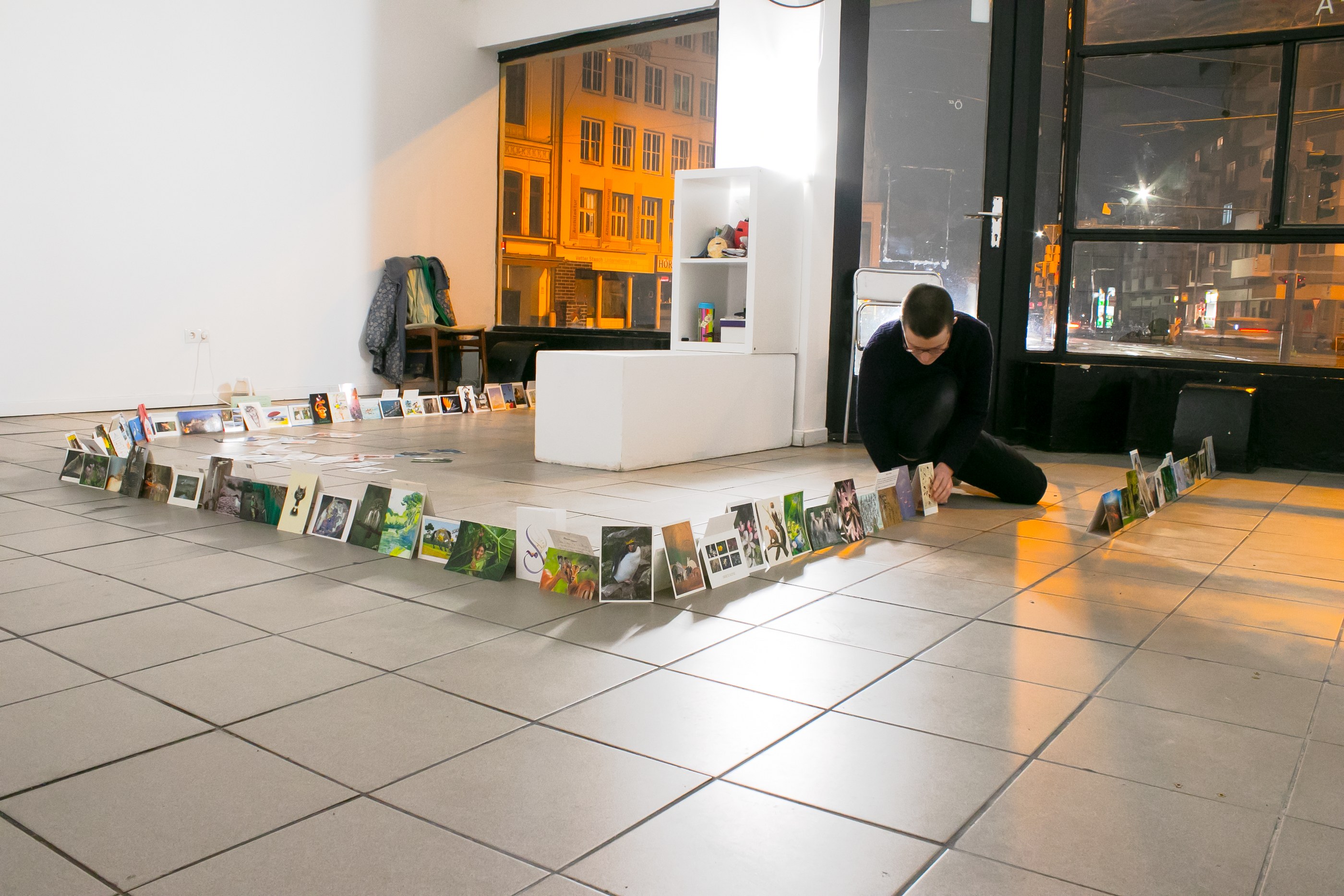 Eddie de Goër arranging postcards into a line by making pairs of postcards stand back to back against each other