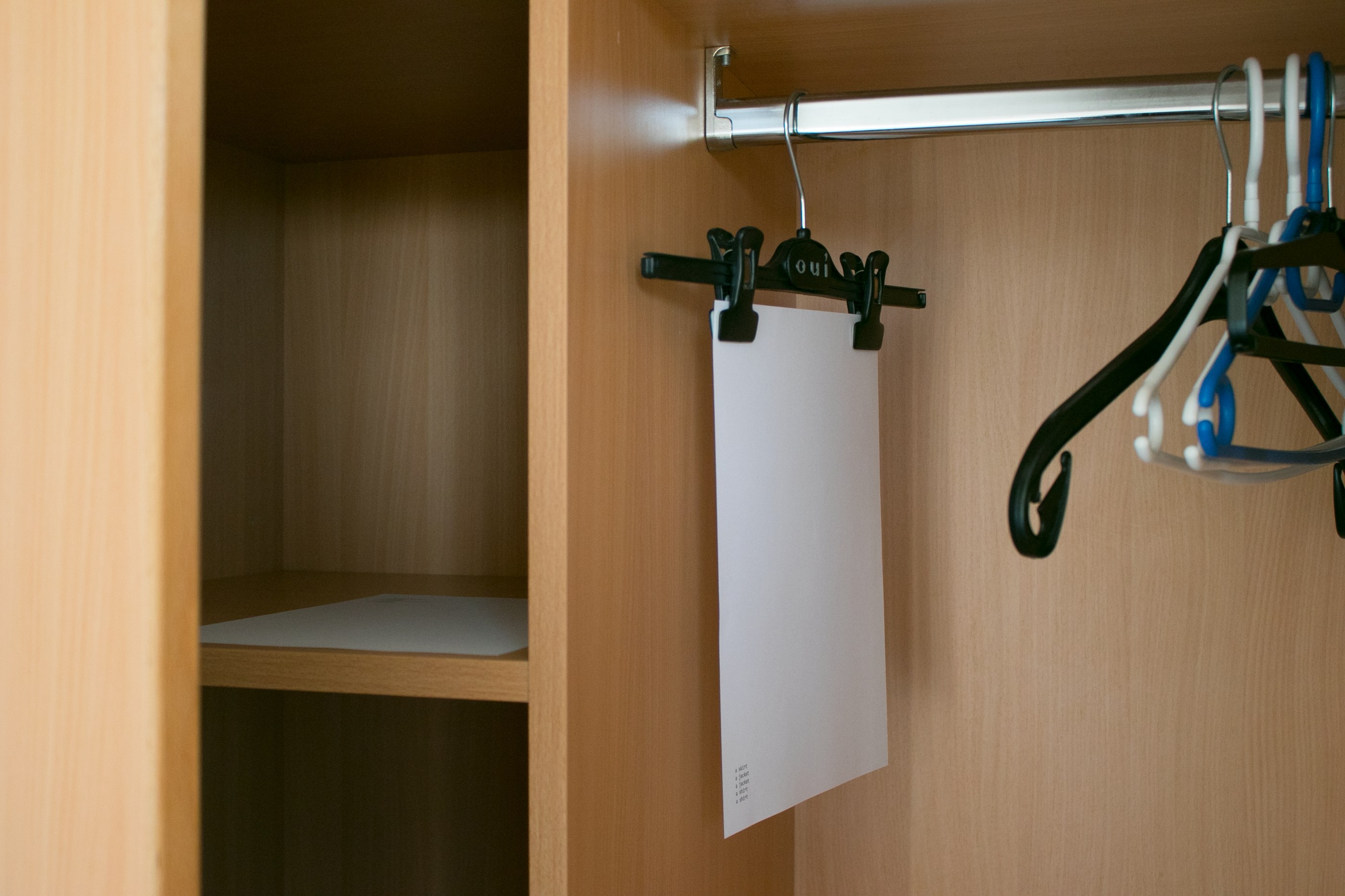 A list is hanged from a trouser hanger inside a closet