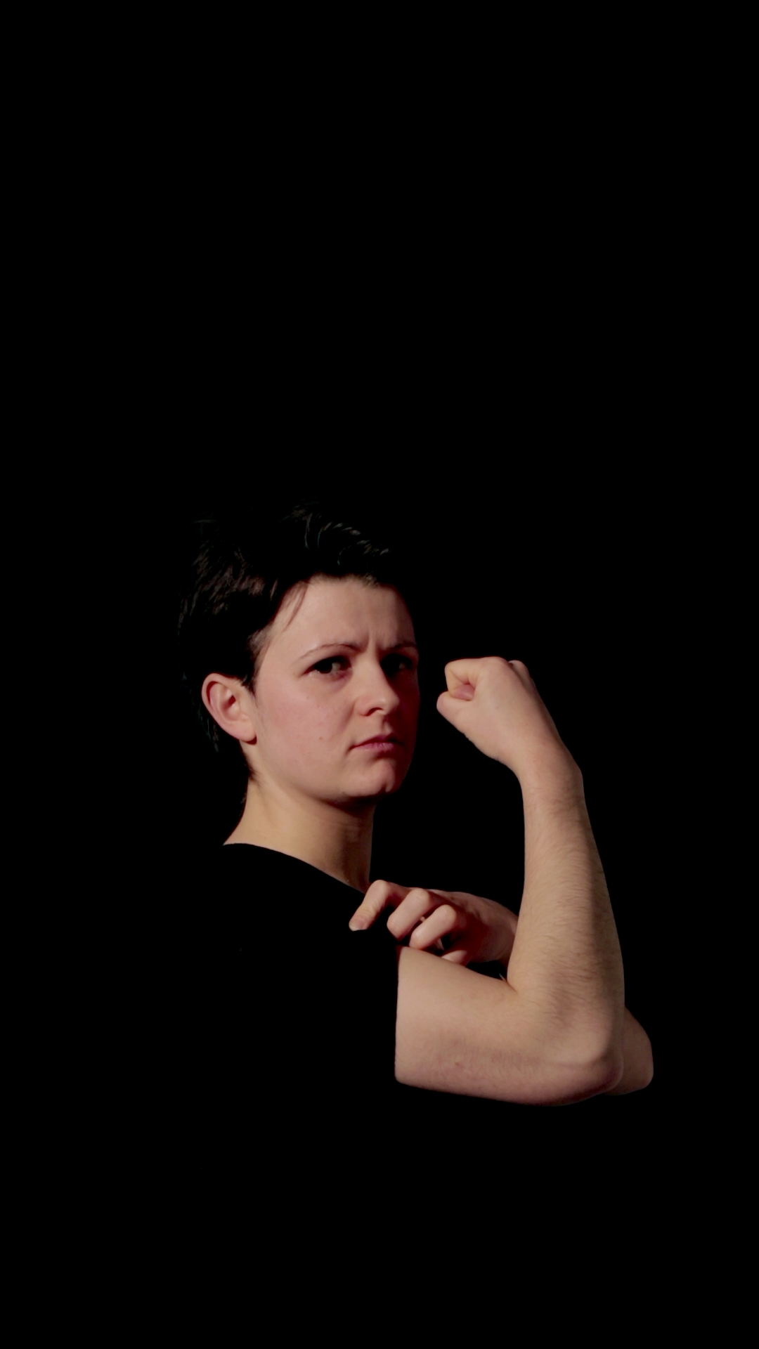 Film still showing a person holding their first up, looking at the camera with a confused look