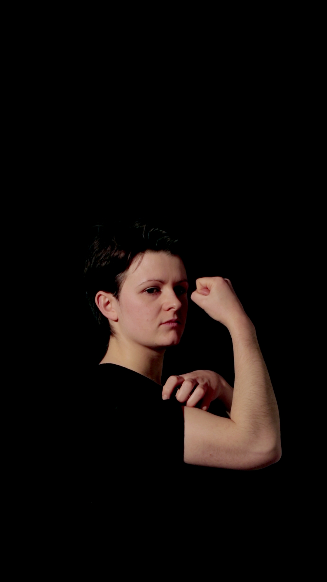 Film still with a slight variation of the arm and hand position, the person is looking down and away from the camera
