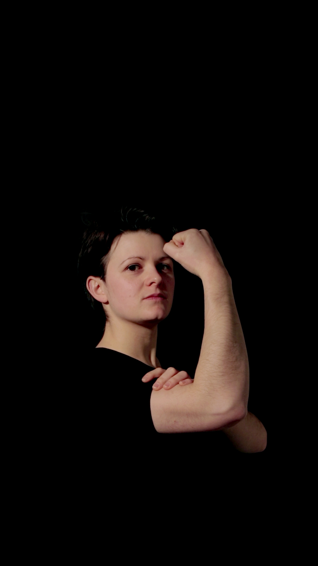 The person is holding their first and head higher up with a somewhat confident look, the pose is closer to the original 