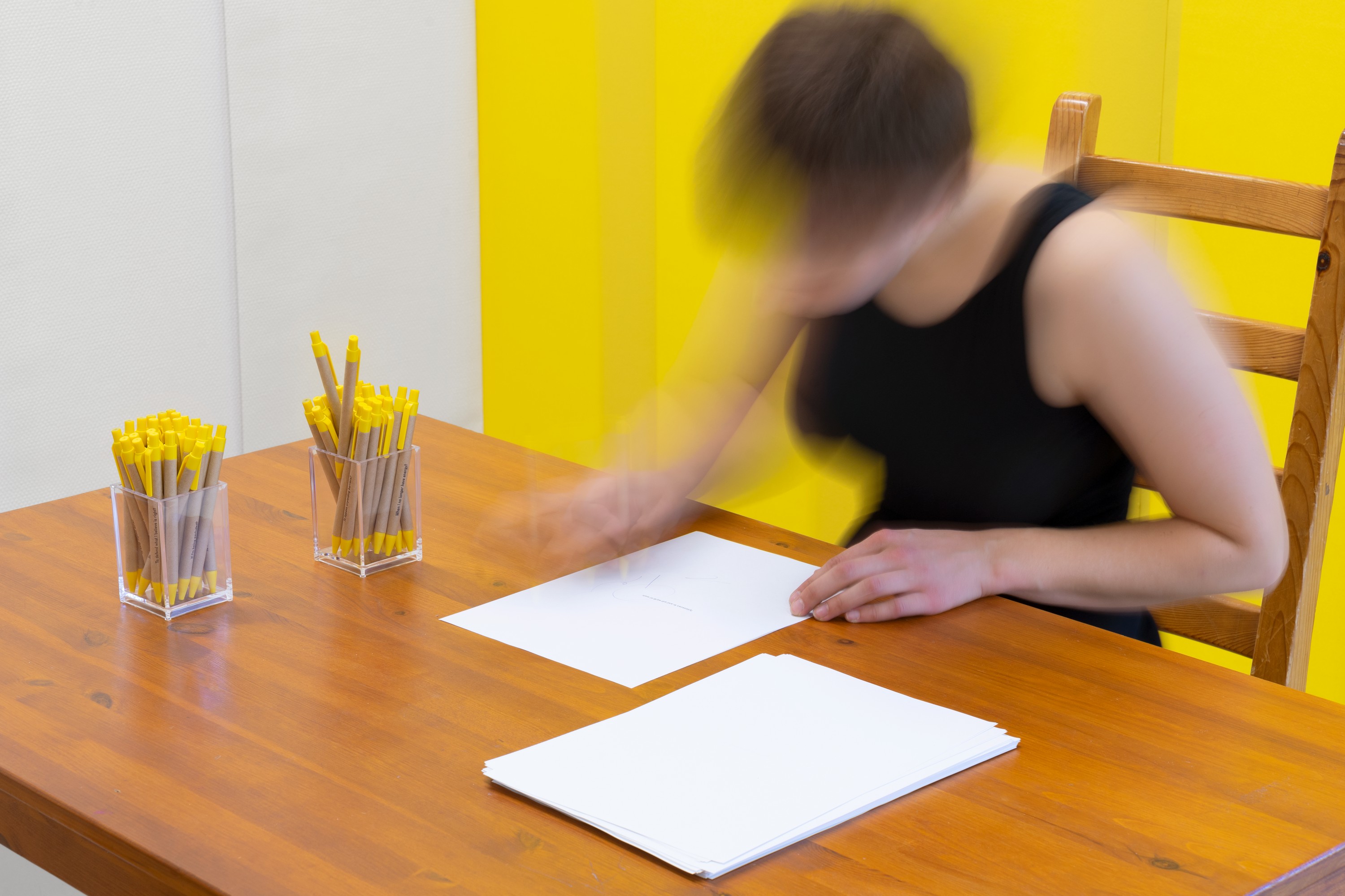 A person is sitting at the desk and writing on the paper