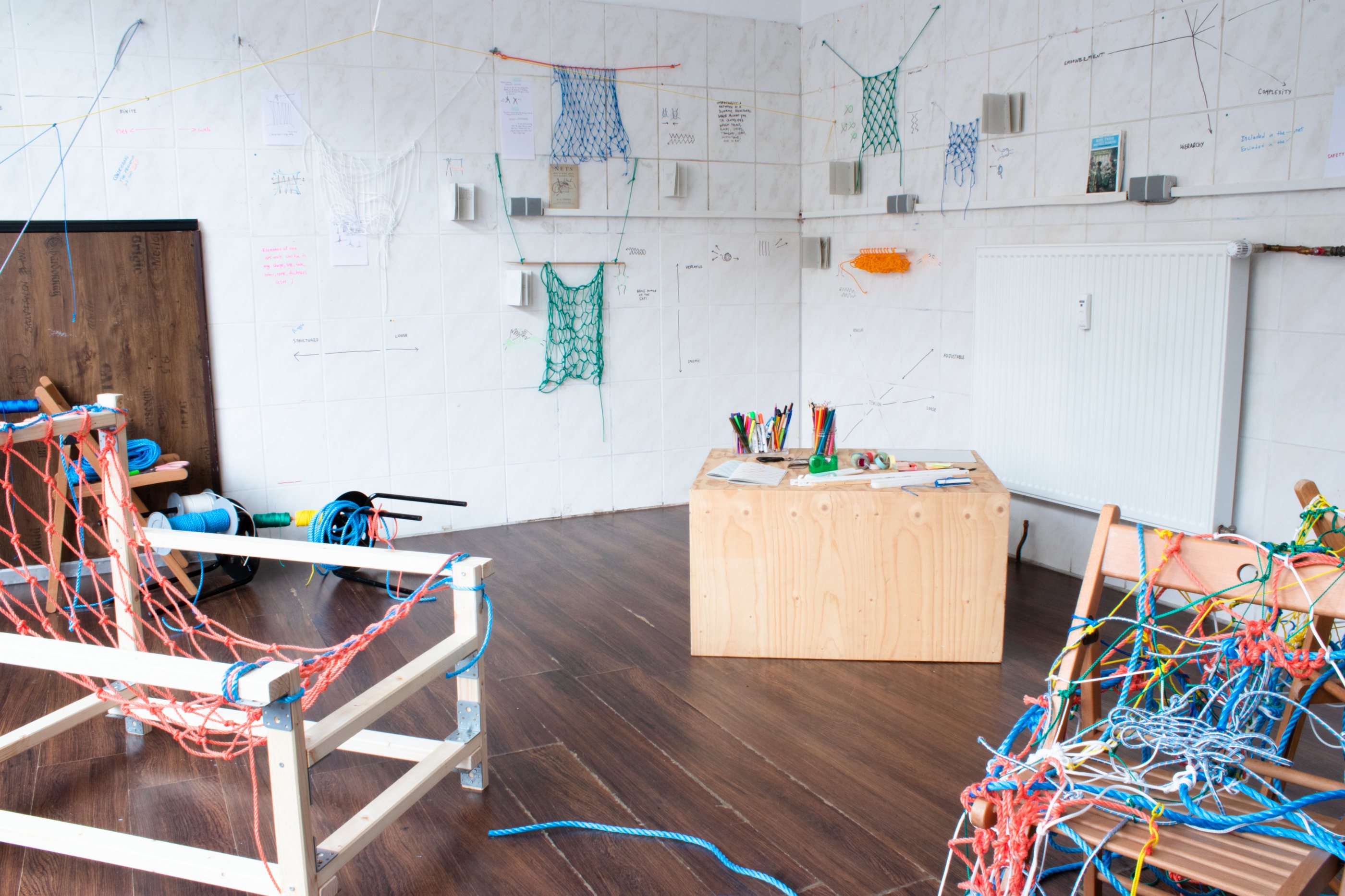 large view of the room showing various pieces of netting, drawings, and objects