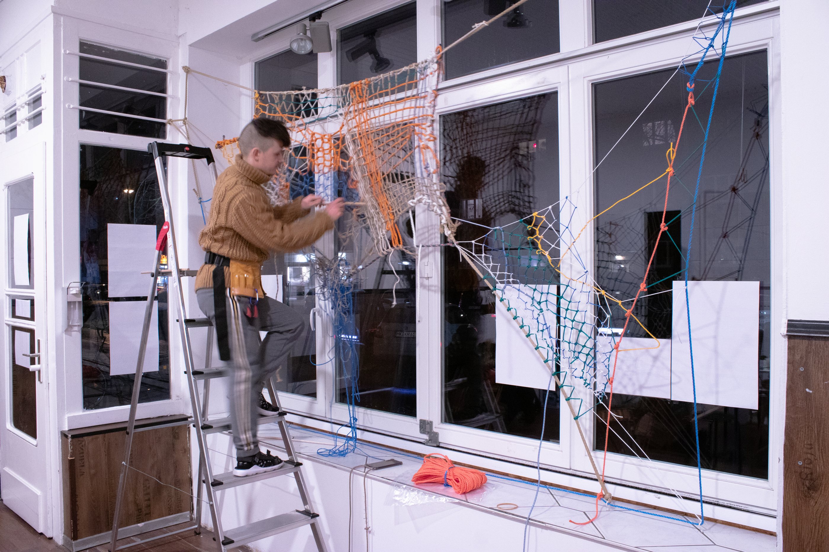 Eddie de Goër working on a net suspended across a window